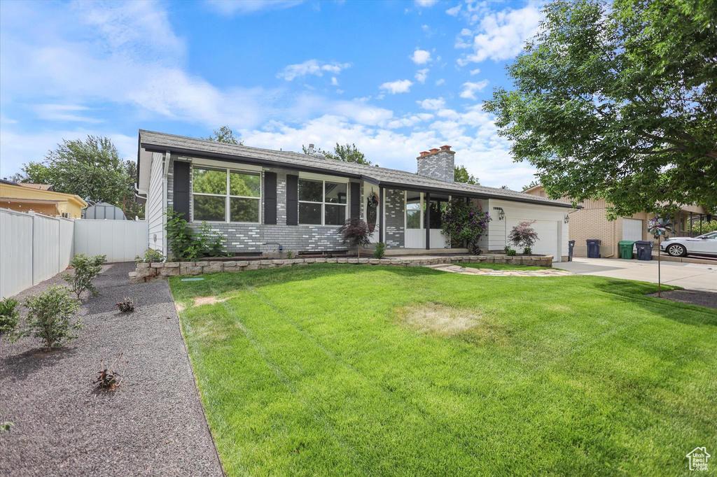 View of front of property with concrete driveway, an attached garage, a chimney, and brick siding