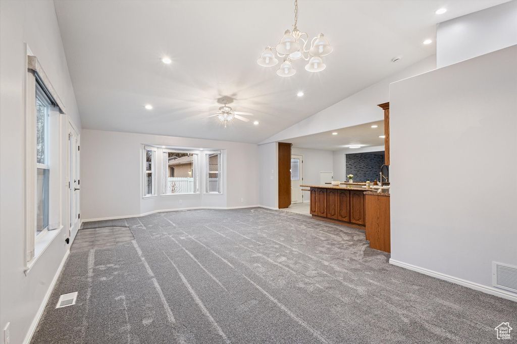 Unfurnished living room with vaulted ceiling, baseboards, light carpet, recessed lighting, and a chandelier