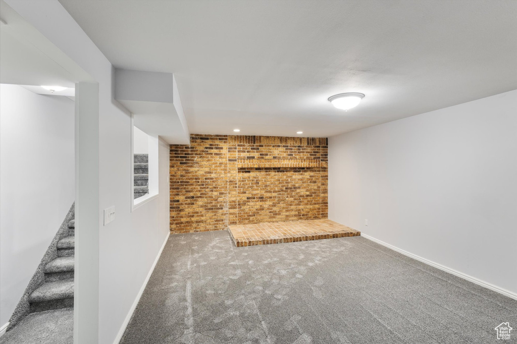 Finished basement with brick wall, carpet flooring, stairway, baseboards, and recessed lighting