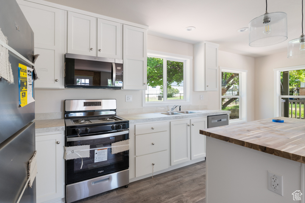 Kitchen with appliances with stainless steel finishes, wood counters, a sink, dark wood-type flooring, and white cabinets