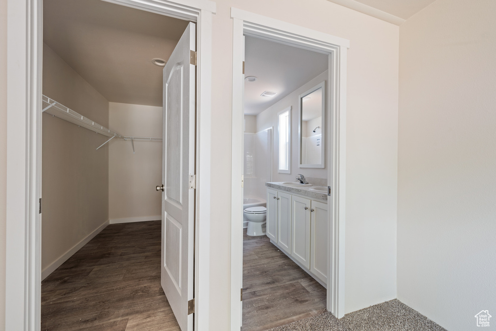 Bathroom with vanity, toilet, wood finished floors, and a spacious closet