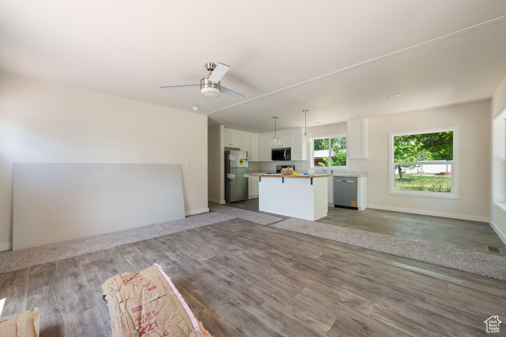 Unfurnished living room featuring ceiling fan, wood finished floors, and baseboards