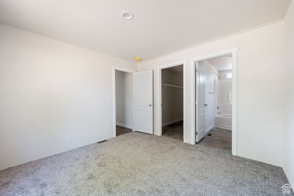 Unfurnished bedroom with carpet floors, a spacious closet, a closet, and connected bathroom