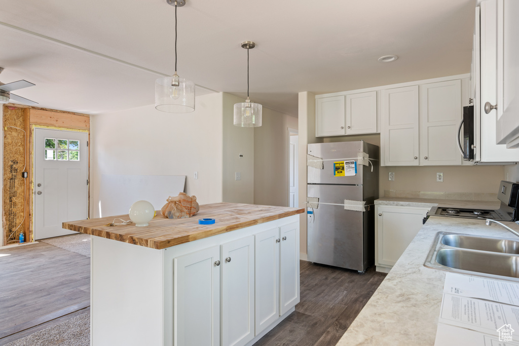 Kitchen featuring freestanding refrigerator, range, wooden counters, a sink, and dark wood-type flooring