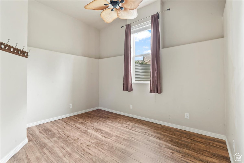 Unfurnished room with wood finished floors, a ceiling fan, and baseboards