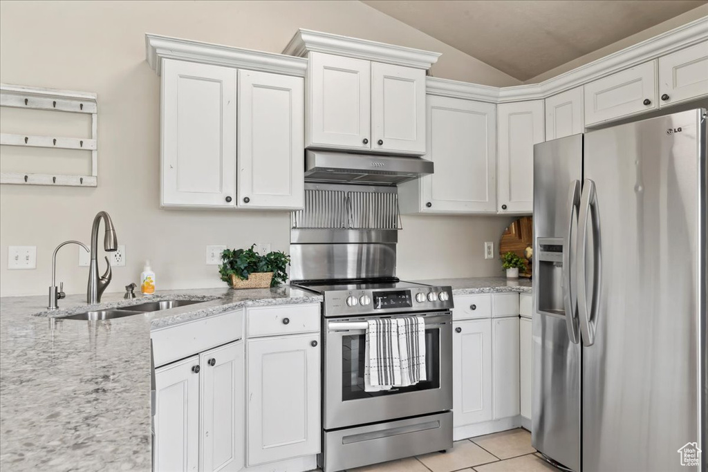 Kitchen with stainless steel appliances, under cabinet range hood, a sink, lofted ceiling, and light stone countertops