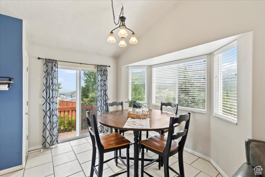 Dining room with light tile patterned flooring, a chandelier, vaulted ceiling, and baseboards