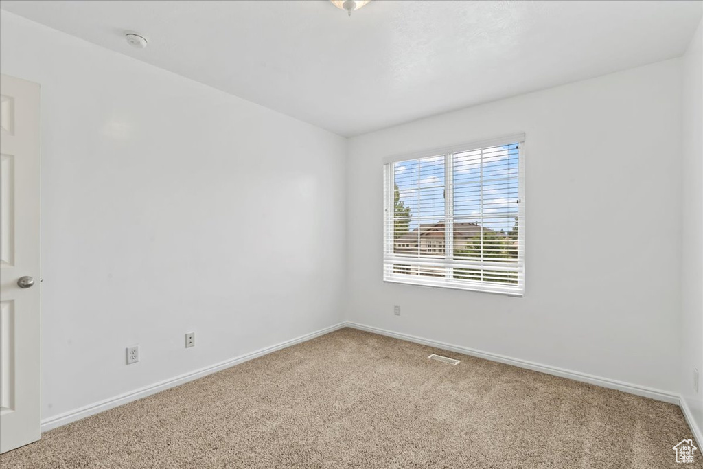 Carpeted spare room featuring baseboards and a smoke detector