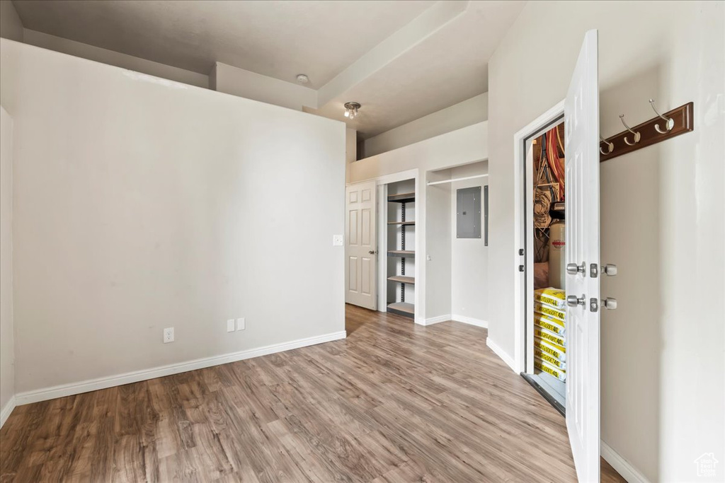 Empty room with wood finished floors, baseboards, and electric panel
