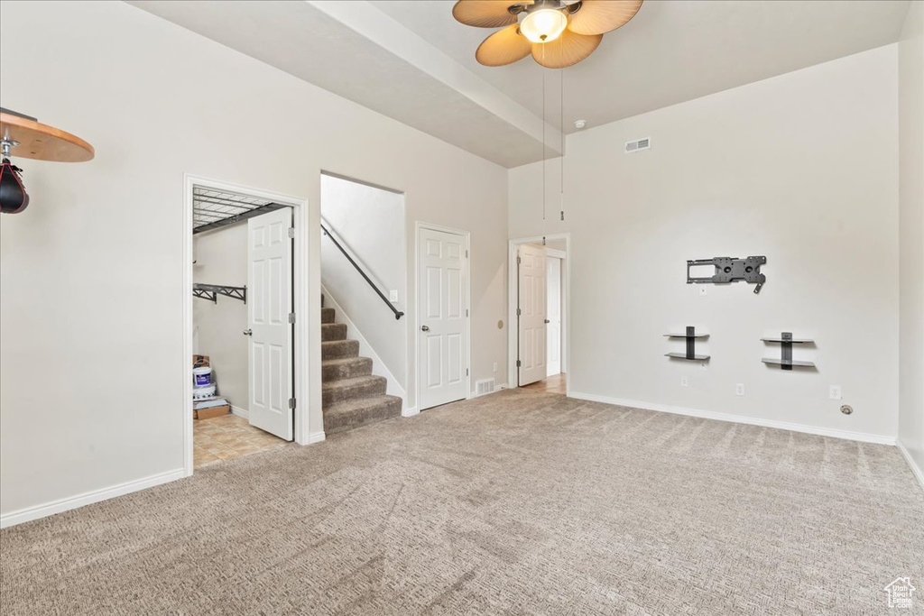 Spare room featuring carpet floors, ceiling fan, stairway, and baseboards