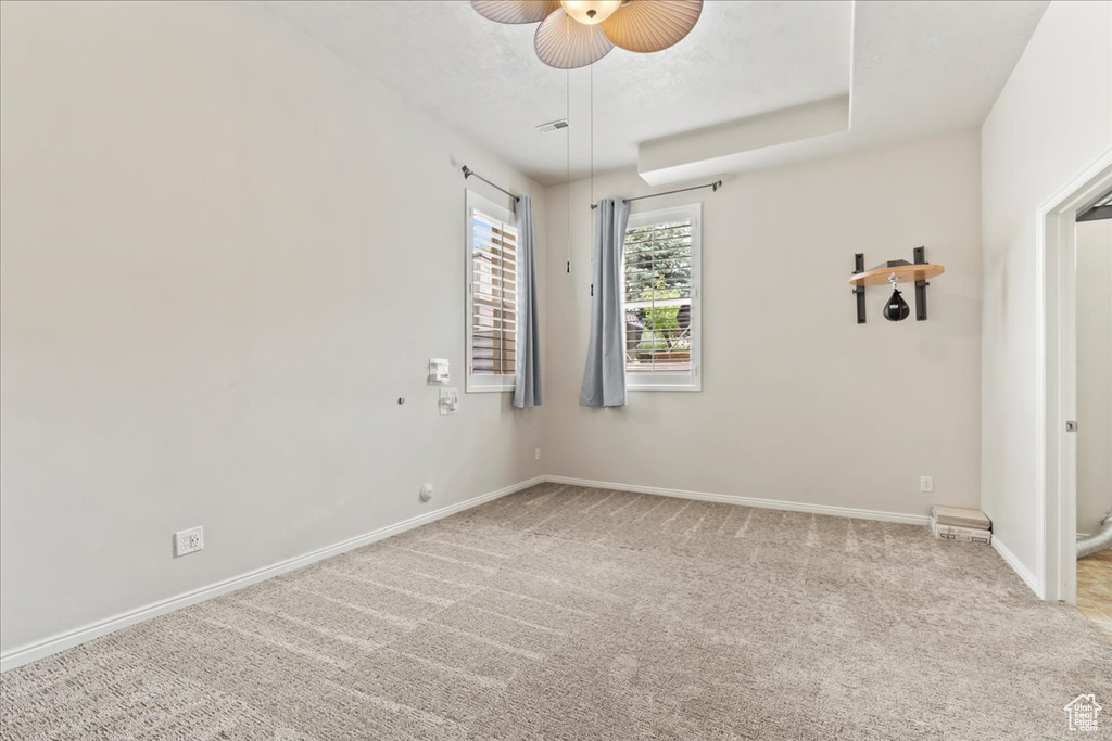 Spare room featuring a ceiling fan, light carpet, and baseboards