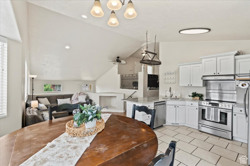Dining area featuring lofted ceiling, a chandelier, light tile patterned flooring, and ceiling fan