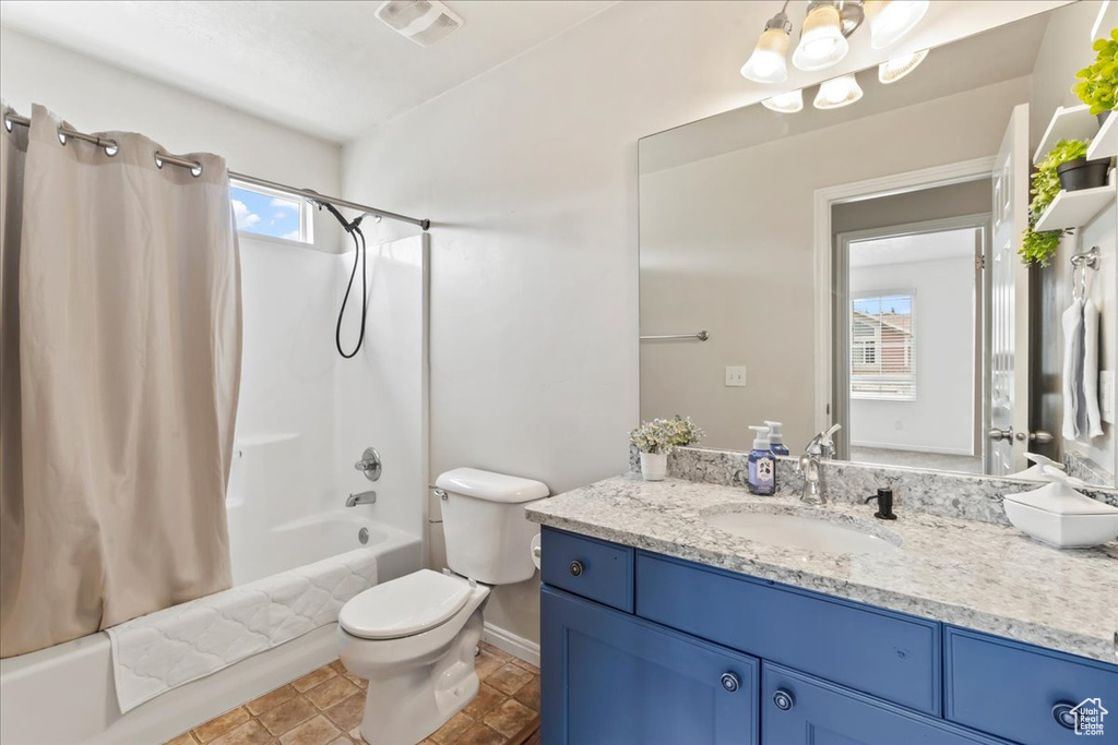 Full bath with vanity, shower / bath combo, toilet, and baseboards