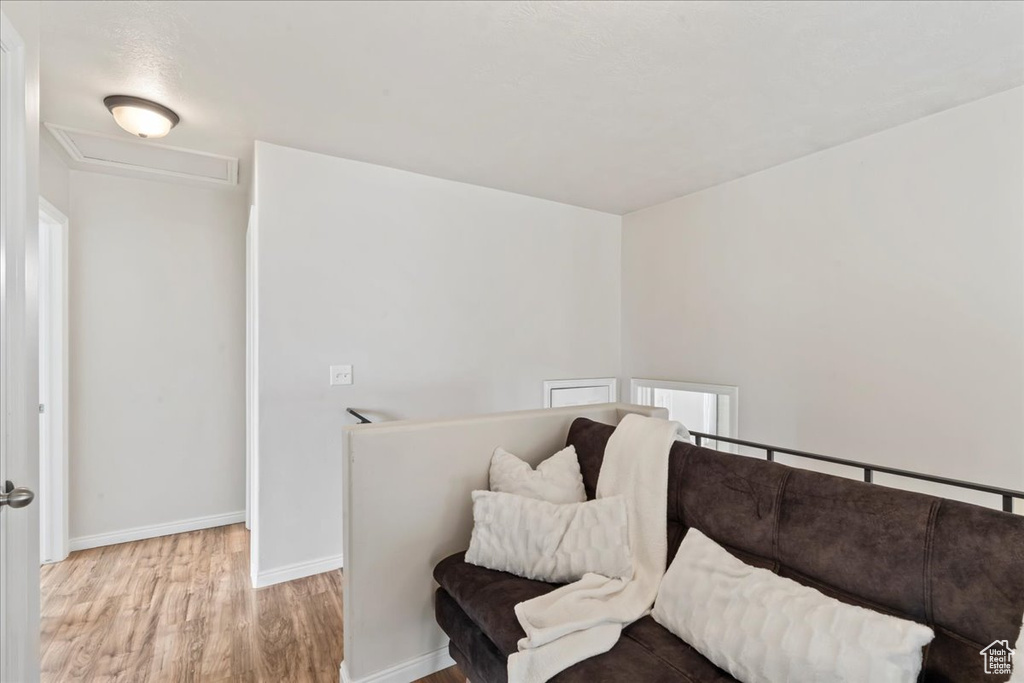 Living area with wood finished floors, attic access, baseboards, and an upstairs landing