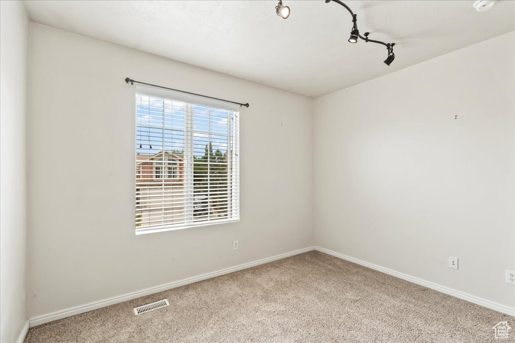 Unfurnished room featuring carpet floors, baseboards, and track lighting