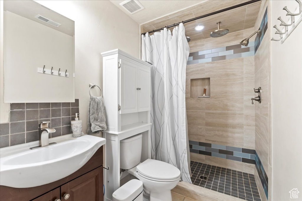 Bathroom featuring toilet, vanity, tiled shower, and tile patterned floors