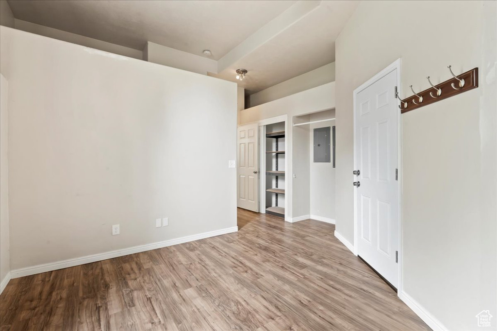 Unfurnished room featuring light wood-style flooring, baseboards, and electric panel