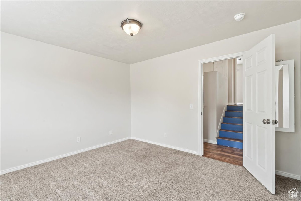 Carpeted spare room featuring baseboards and a smoke detector