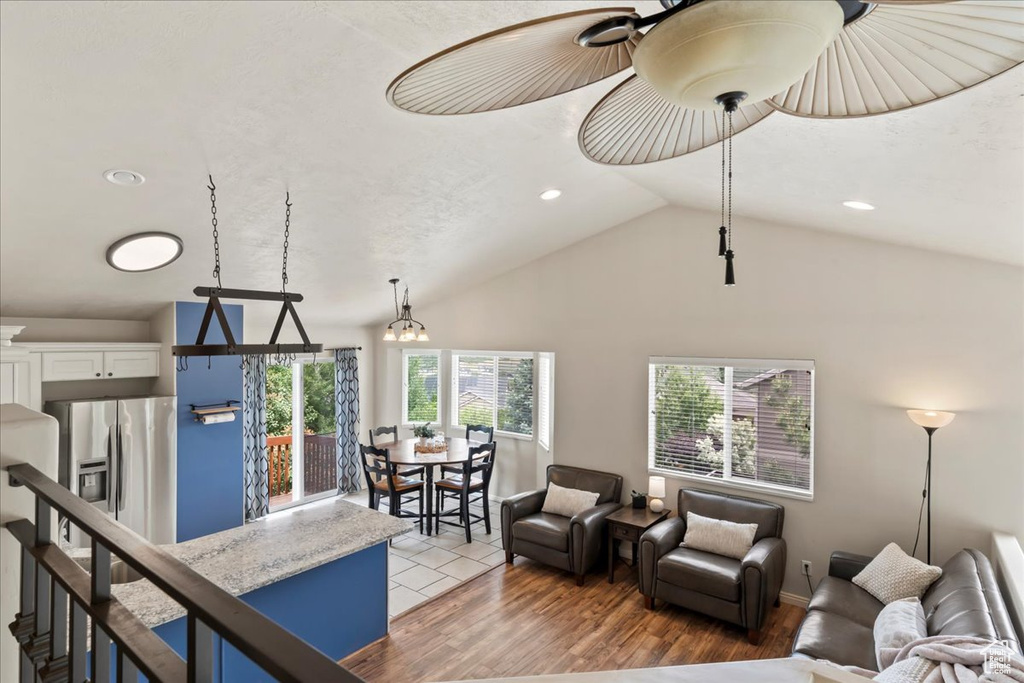 Living area with vaulted ceiling, recessed lighting, light wood finished floors, and baseboards