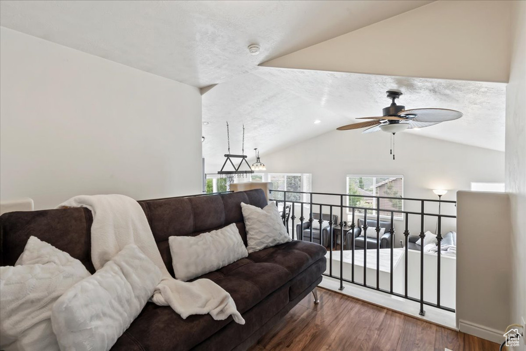 Living room with wood finished floors, lofted ceiling, and a ceiling fan