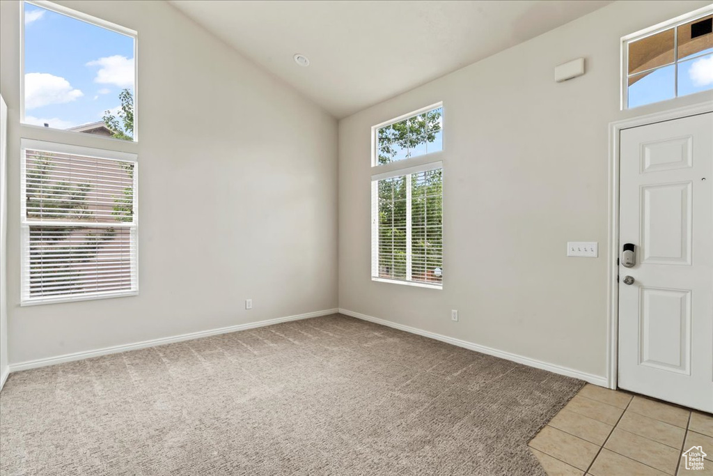 Entryway with baseboards, light carpet, light tile patterned floors, and high vaulted ceiling