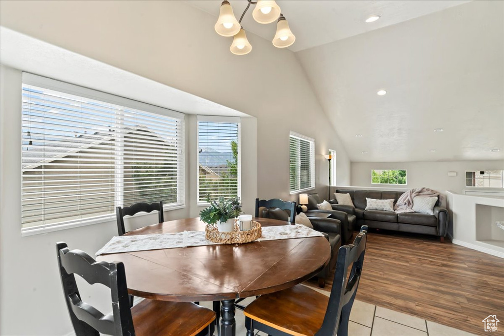 Dining area with lofted ceiling, light tile patterned floors, a chandelier, and recessed lighting