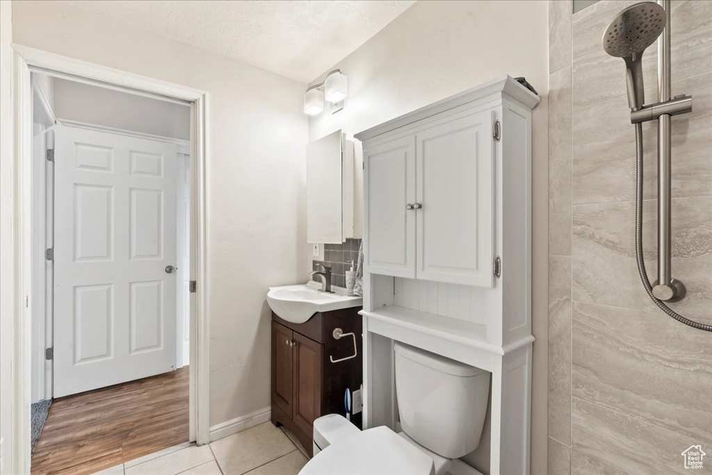 Bathroom featuring vanity, tiled shower, toilet, and tile patterned flooring
