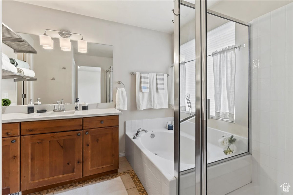 Bathroom featuring vanity, a shower stall, a bath, and inlaid floor details