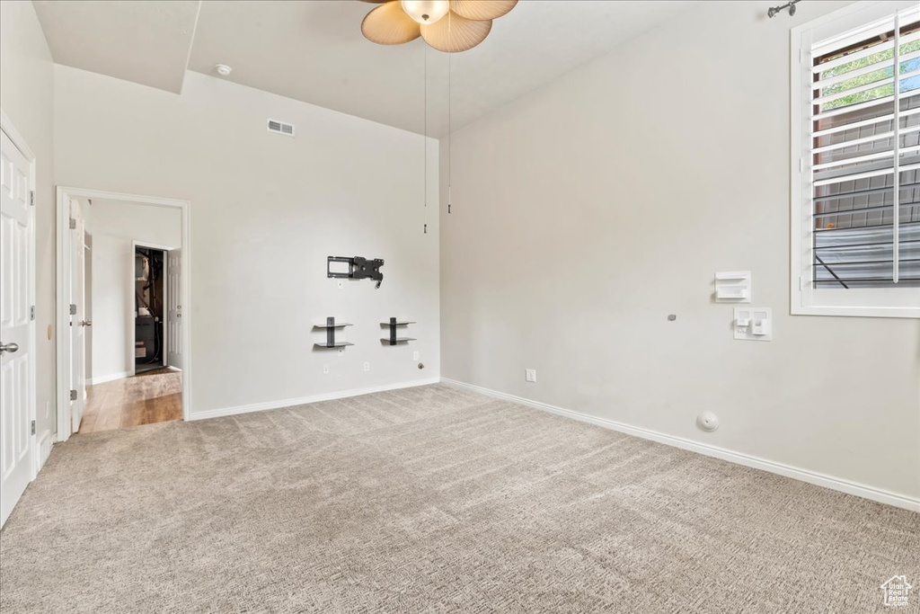 Carpeted empty room featuring a ceiling fan and baseboards