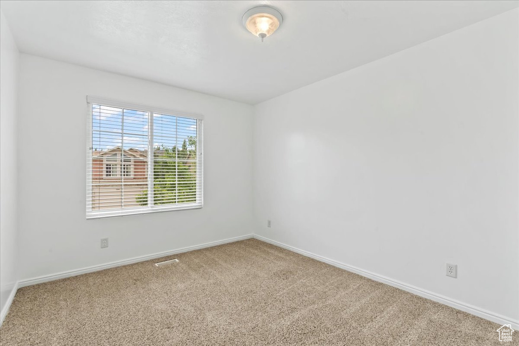 Carpeted spare room featuring baseboards