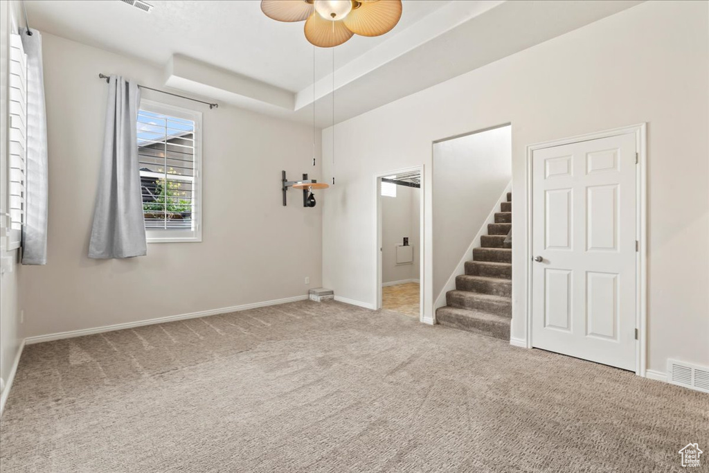 Carpeted empty room with stairway, ceiling fan, and baseboards