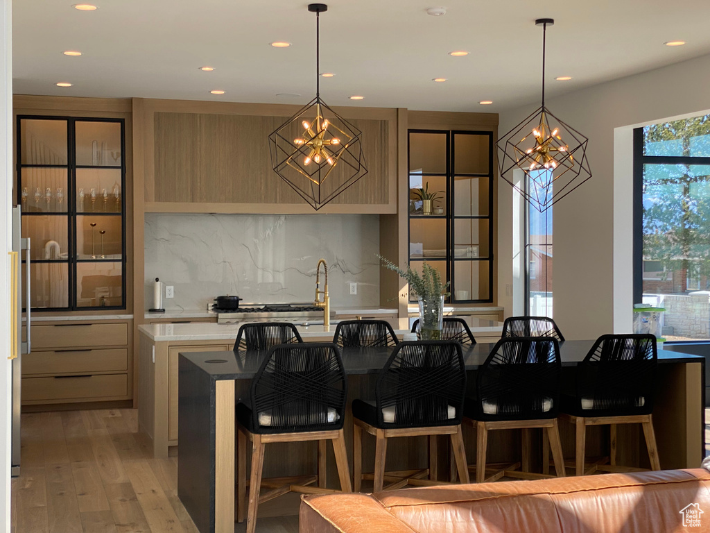 Kitchen with a chandelier, recessed lighting, light countertops, decorative backsplash, and light wood-style flooring