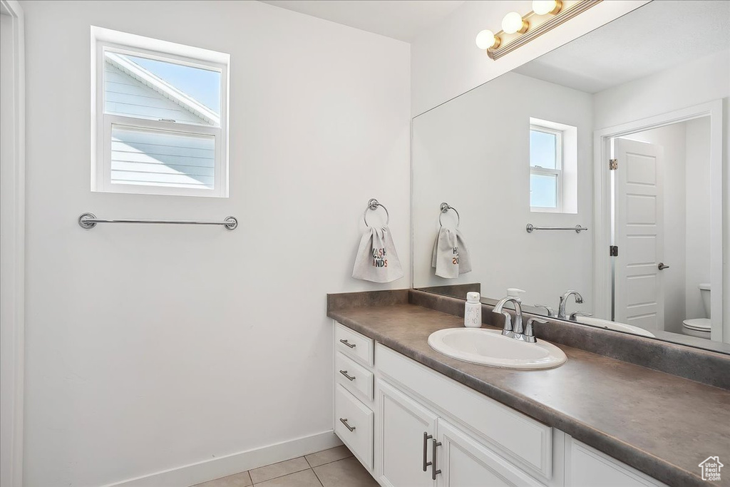 Bathroom featuring vanity, toilet, tile patterned floors, and baseboards
