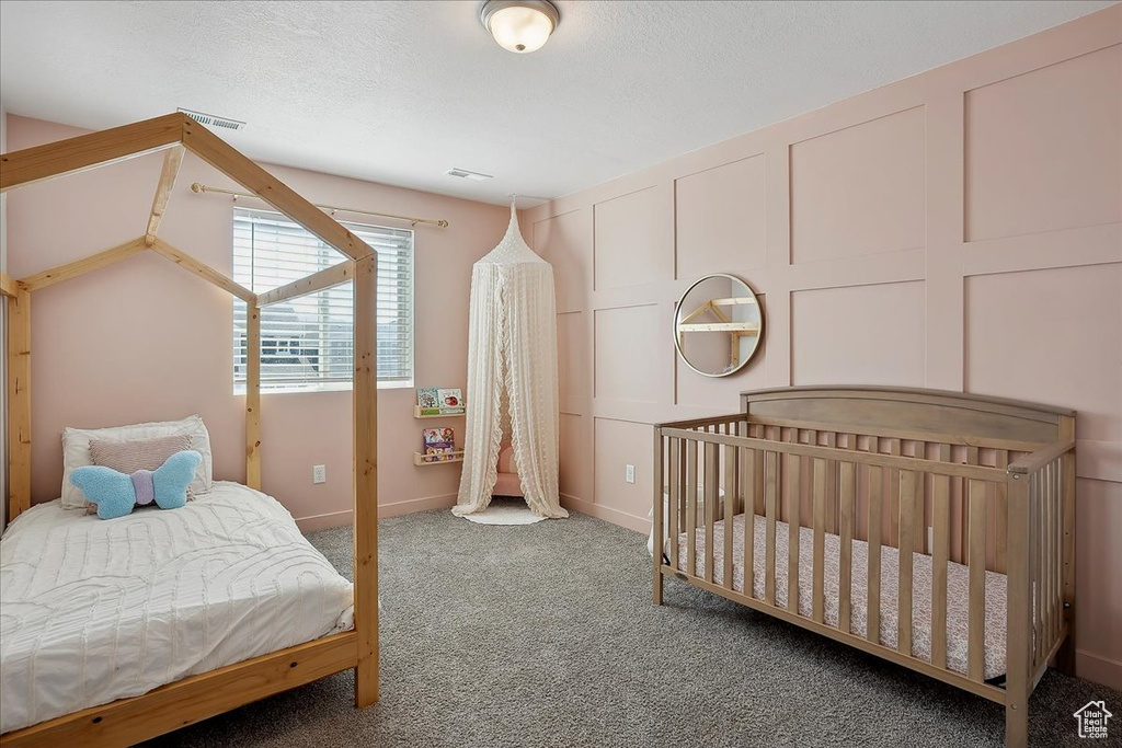 Bedroom featuring carpet floors, a decorative wall, and baseboards