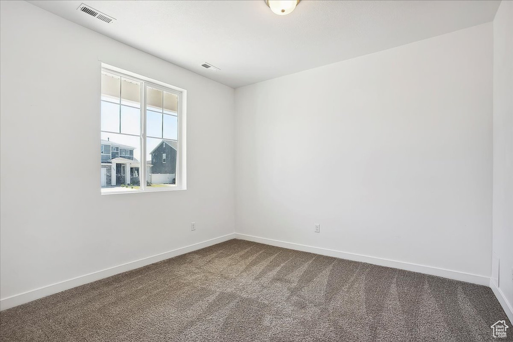 Unfurnished room with dark colored carpet and baseboards
