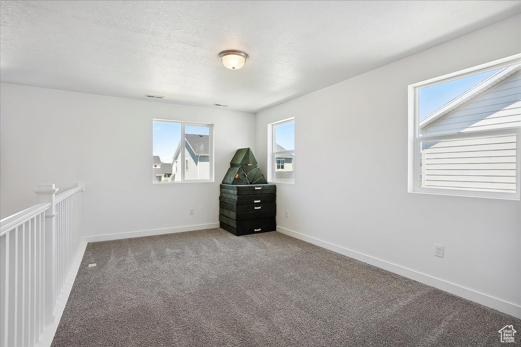 Carpeted empty room with baseboards and a textured ceiling