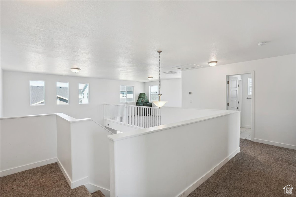 Hallway featuring an upstairs landing, carpet flooring, baseboards, and attic access