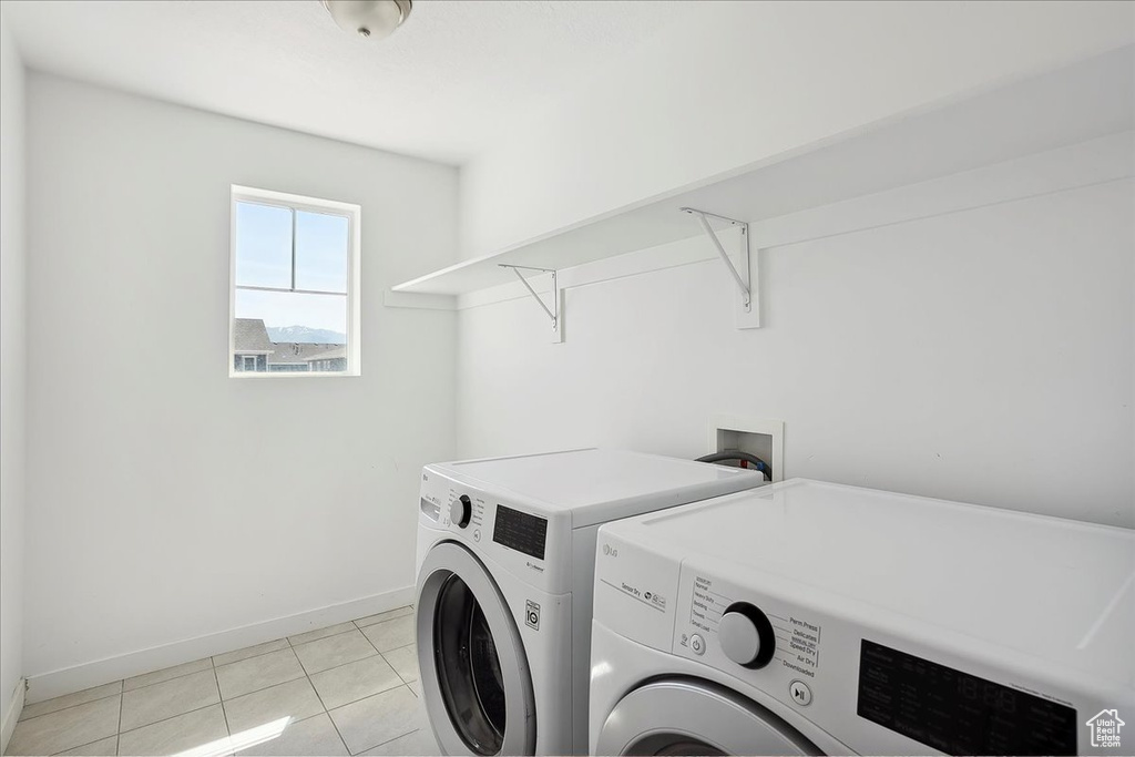 Laundry area with washer and dryer, baseboards, and light tile patterned floors