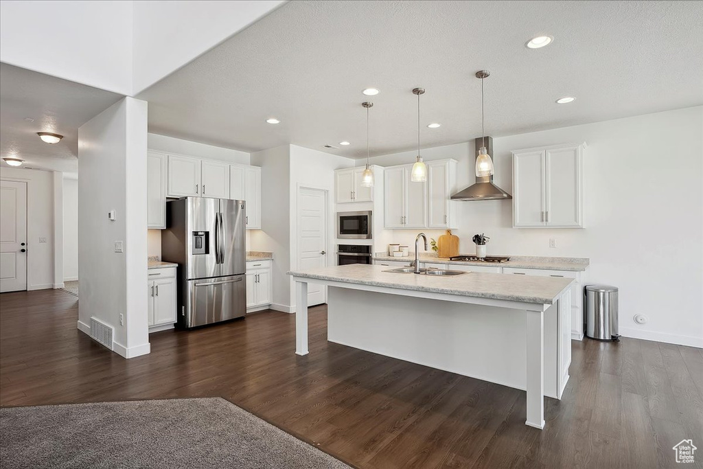Kitchen with appliances with stainless steel finishes, a sink, wall chimney exhaust hood, dark wood-style floors, and recessed lighting