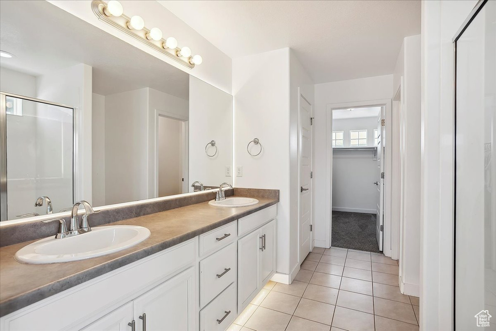 Bathroom with tile patterned flooring, double vanity, a stall shower, and baseboards