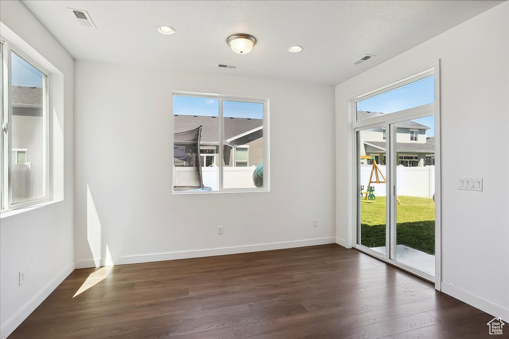 Empty room with plenty of natural light, dark wood-type flooring, baseboards, and recessed lighting