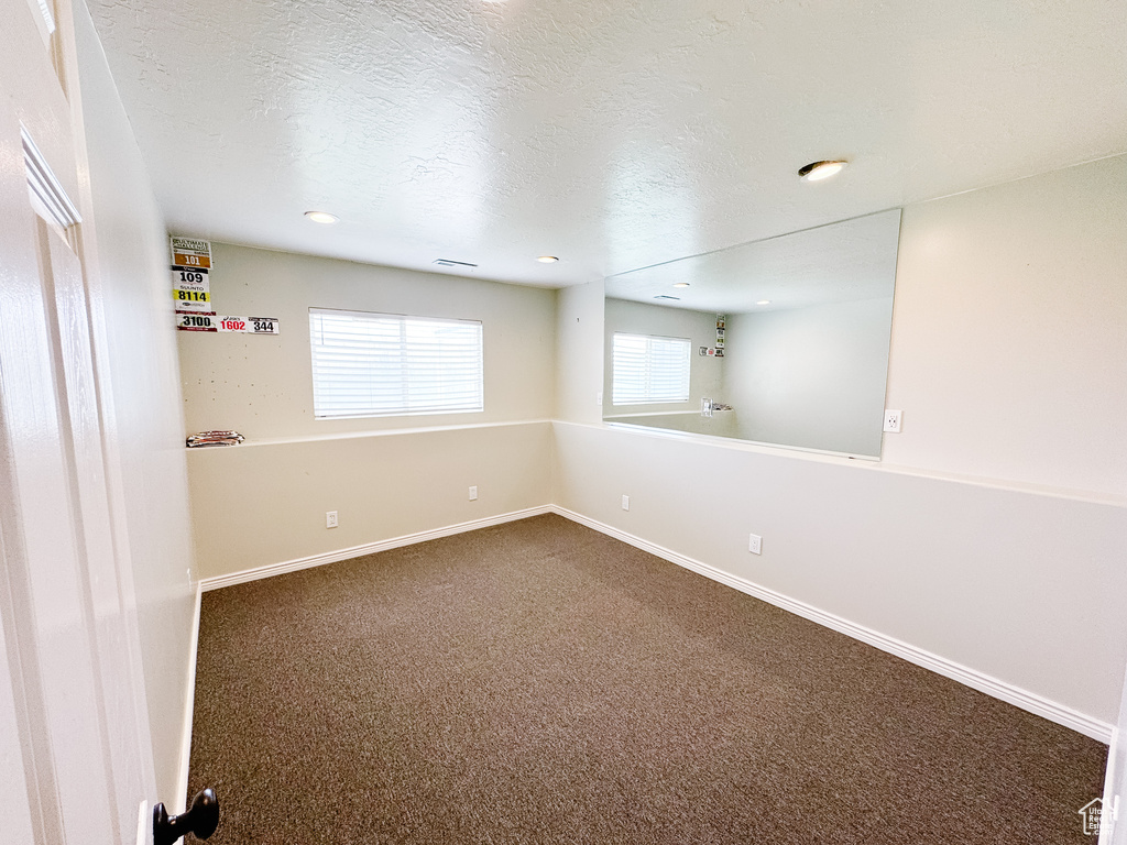 Spare room with dark carpet, baseboards, a textured ceiling, and recessed lighting