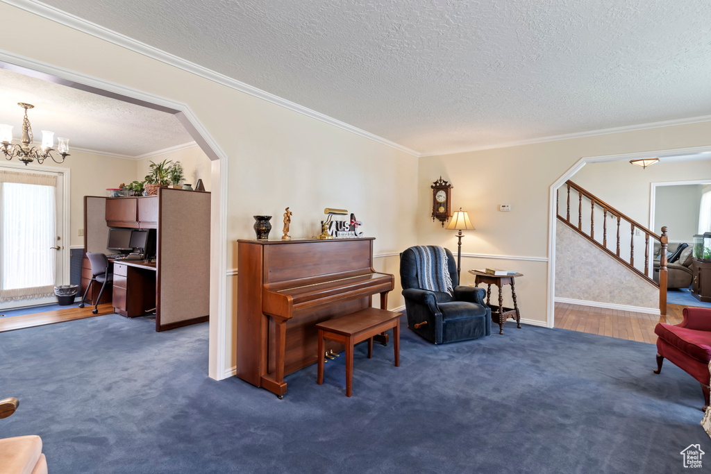 Sitting room with a textured ceiling, a chandelier, stairway, arched walkways, and an office area