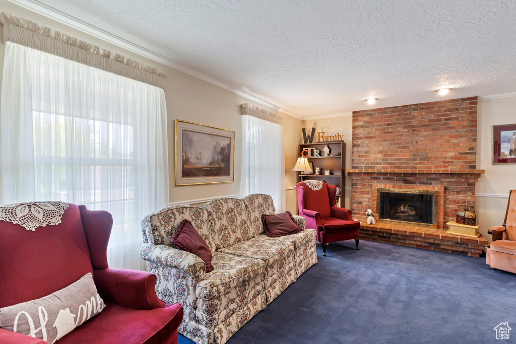 Living area featuring a textured ceiling, crown molding, carpet flooring, and a brick fireplace