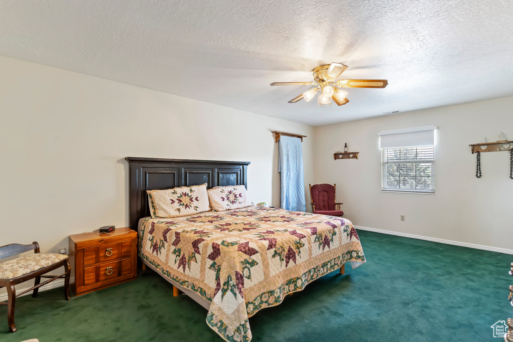 Carpeted bedroom with a ceiling fan, a textured ceiling, and baseboards