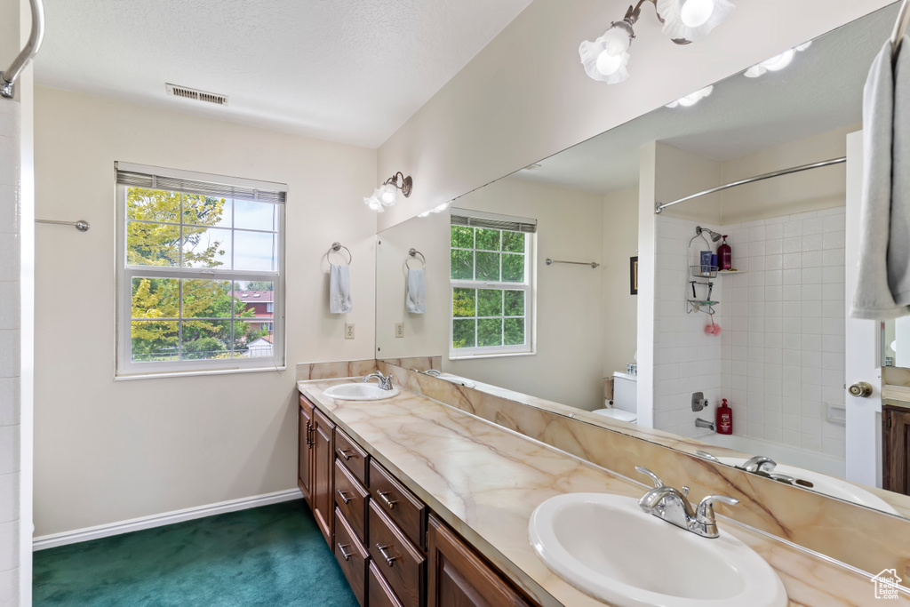 Full bathroom with double vanity, plenty of natural light, baseboards, and tub / shower combination
