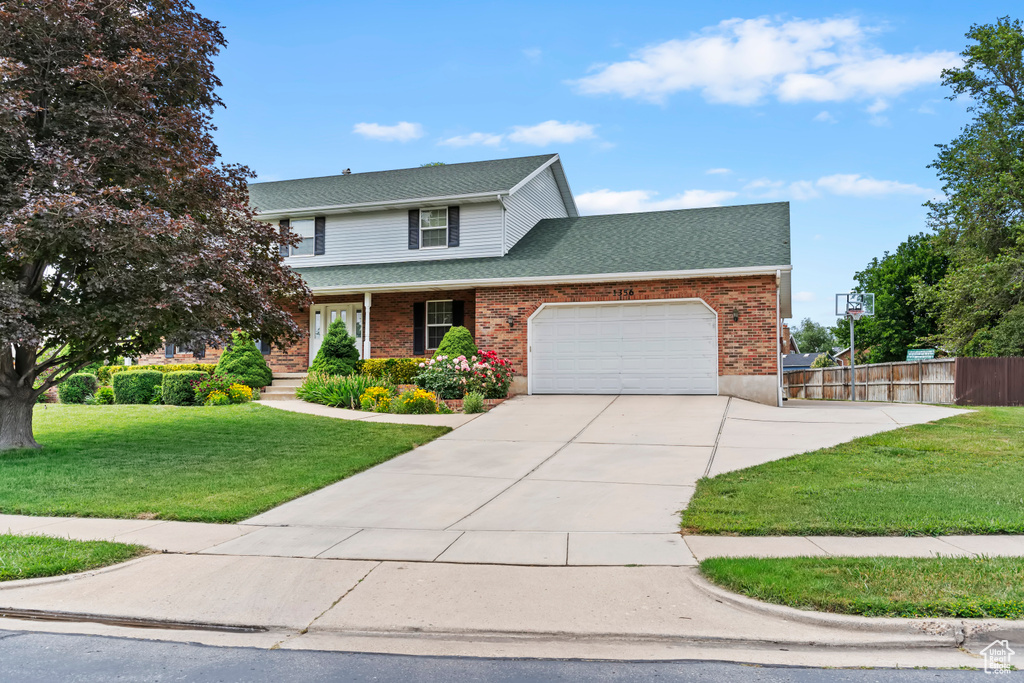 Traditional-style home with a garage, concrete driveway, a shingled roof, brick siding, and a porch