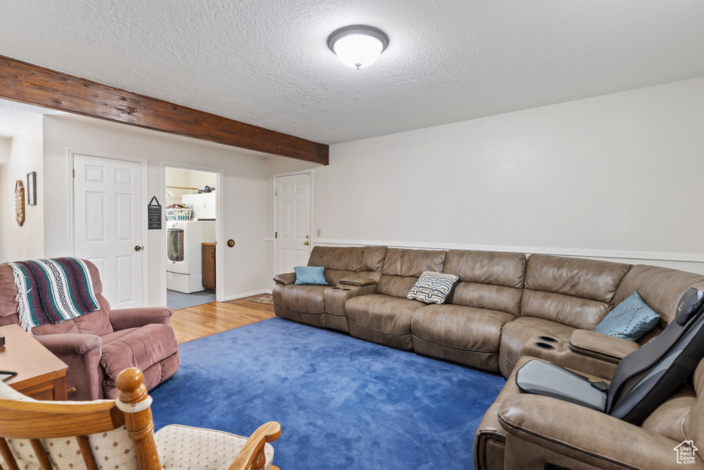 Living room featuring wood finished floors, washer / dryer, and a textured ceiling