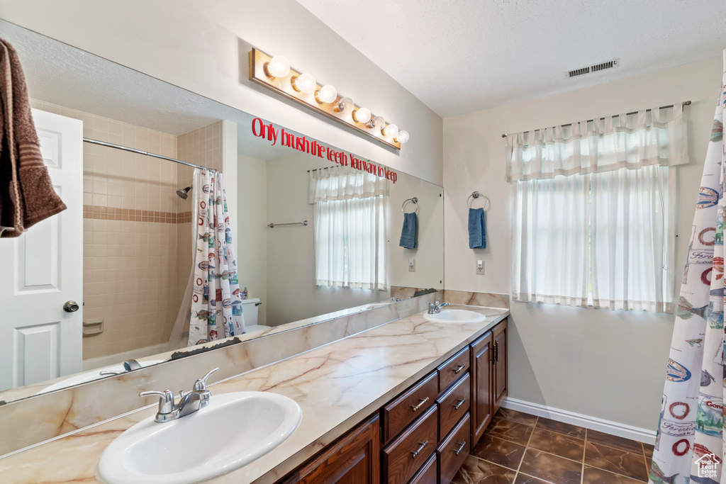 Bathroom featuring double vanity, toilet, tile patterned floors, and baseboards