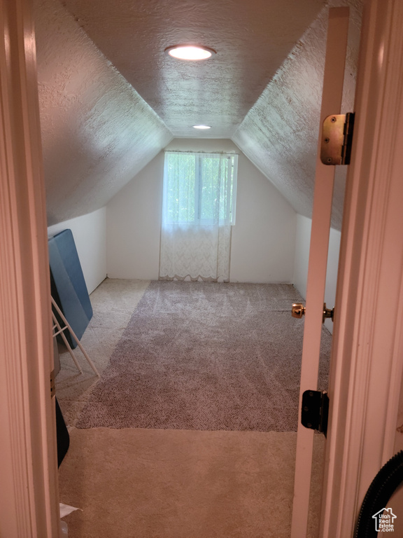 Bonus room with carpet flooring, a textured ceiling, and lofted ceiling